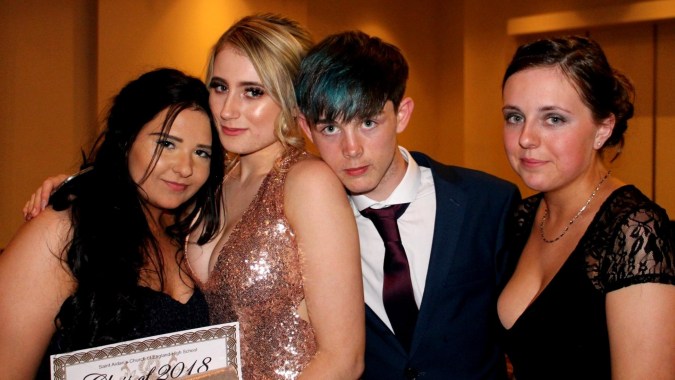 Vier Personen in formeller Kleidung posieren gemeinsam bei einer Veranstaltung der St. Aidan's Comprehensive School.