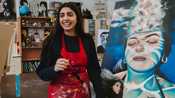 Eine Schülerin der Stamford High School steht vor einem Kunstraum mit vielen Kunstwerken und Regalen.