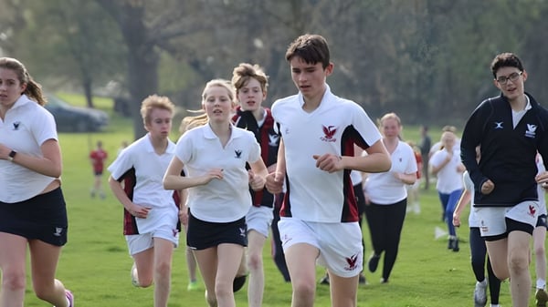 Eine Gruppe Schüler der Stamford High School läuft gemeinsam auf dem Sportfeld zwischen Bäumen.