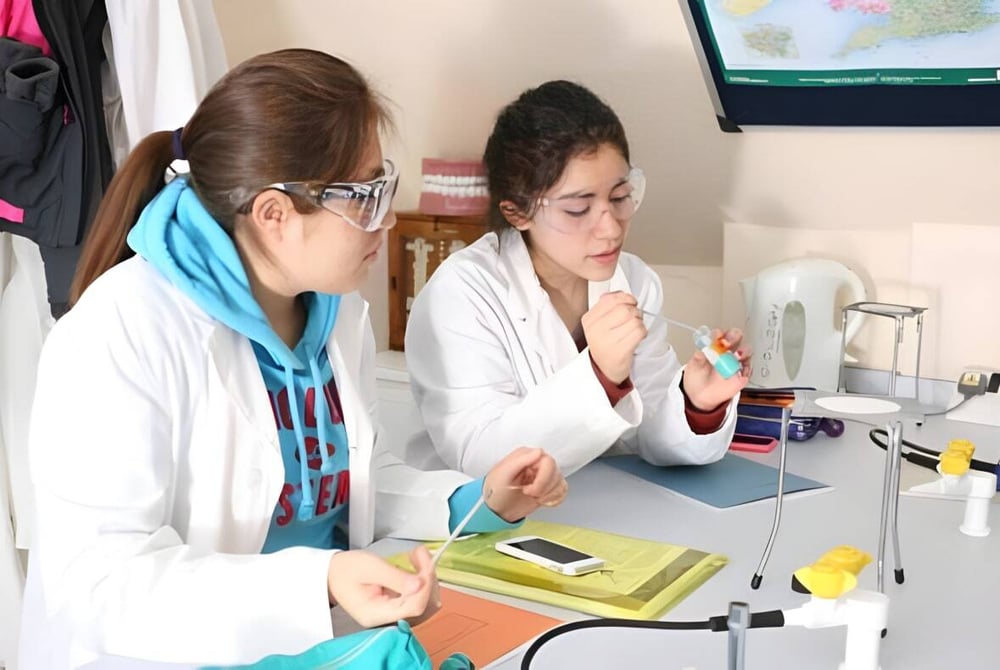 Zwei Schülerinnen des St. Andrew’s College Cambridge arbeiten gemeinsam im Labor an wissenschaftlichen Experimenten.