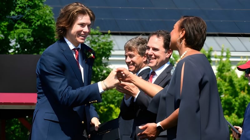 Eine Gruppe von Männern in formeller Kleidung versammelt sich im Garten der St. Anne's-Belfield School.