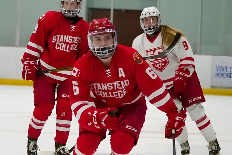 Eine Gruppe von Hockeyspielern in roten und weißen Uniformen auf dem Eis des Stanstead College.
