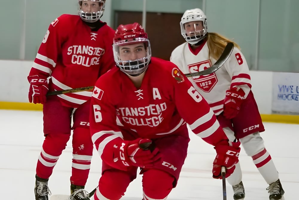 Eine Gruppe von Hockeyspielern in roten und weißen Uniformen auf dem Eis des Stanstead College.