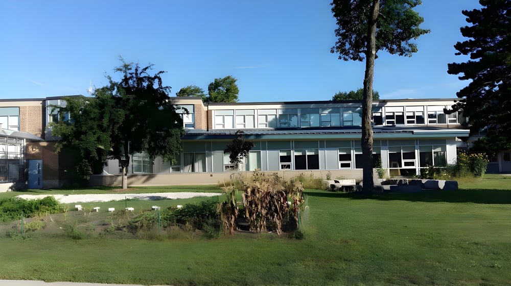 Das moderne Gebäude des Stayner Collegiate Institute ist umgeben von gepflegtem Rasen und Bäumen im Vordergrund.