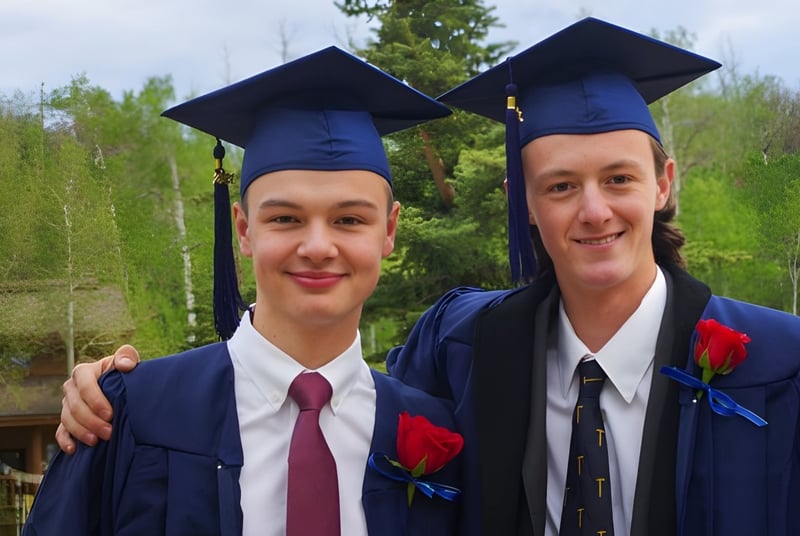 Zwei Schüler der Steamboat Mountain School stehen im Freien in ihren Abschlussroben zusammen.