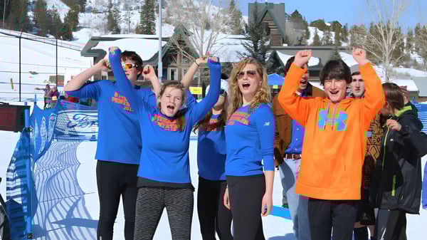 Eine Gruppe von Schülerinnen und Schülern der Steamboat Mountain School steht im Schnee vor einem Skigebiet.