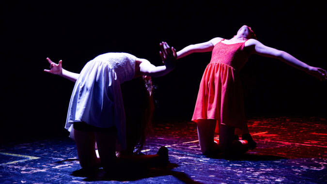 Schüler der St. Edward's School in Poole führen auf einer Bühne mit dunklem Hintergrund und blau beleuchtetem Boden auf.