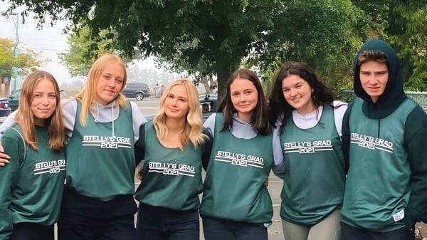 Eine Gruppe von Schülerinnen und Schülern der Stellys Secondary School steht in grünen Trikots im Außenbereich vor Bäumen und Gebäuden.