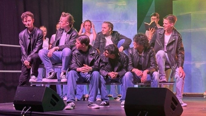 Eine Gruppe Schülerinnen und Schüler steht auf der Bühne der Stepaside Educate Together Secondary School unter buntem Licht.