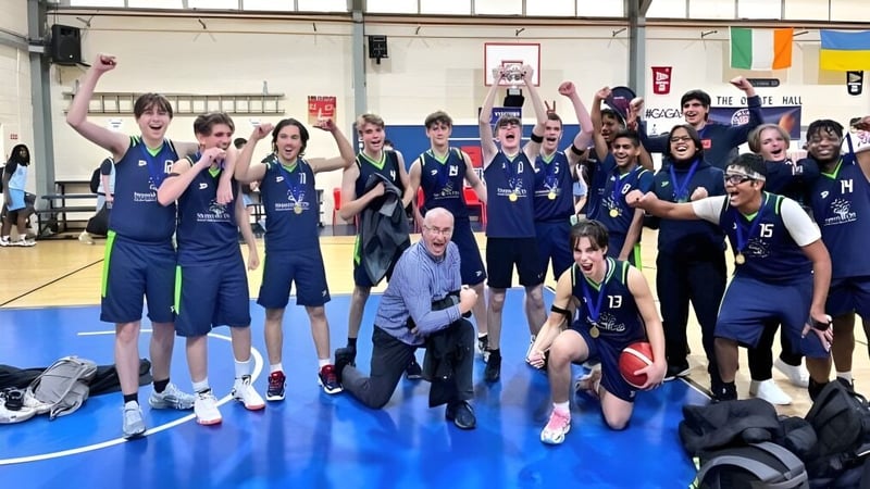 Eine Gruppe von Schülerinnen und Schülern der Stepaside Educate Together Secondary School posiert in der Turnhalle mit Sportgeräten und Bannern im Hintergrund.