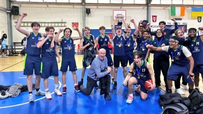 Eine Gruppe von Schülerinnen und Schülern der Stepaside Educate Together Secondary School feiert in der Turnhalle einen Erfolg.