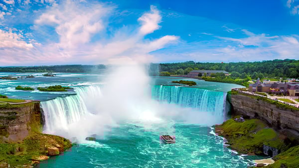 Ein rotes Boot fährt unter einem Wasserfall in einer grünen Landschaft auf dem Gelände des Stephen Leacock Collegiate Institute.