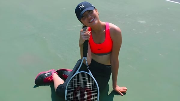 Eine Person mit rotem Tanktop und schwarzen Shorts hält einen Tennisschläger auf dem Tennisplatz des Stephen Leacock Collegiate Institute.