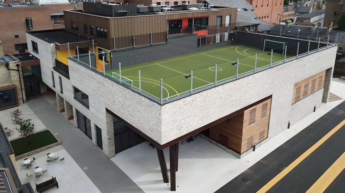 Das mehrstöckige Gebäude der Stephen Perse Foundation mit einem Fußballfeld auf dem Dach in urbaner Umgebung.