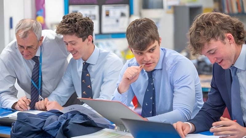 Schüler der Stephen Perse Foundation diskutieren gemeinsam an einem Laptop in einem Bildungsraum.
