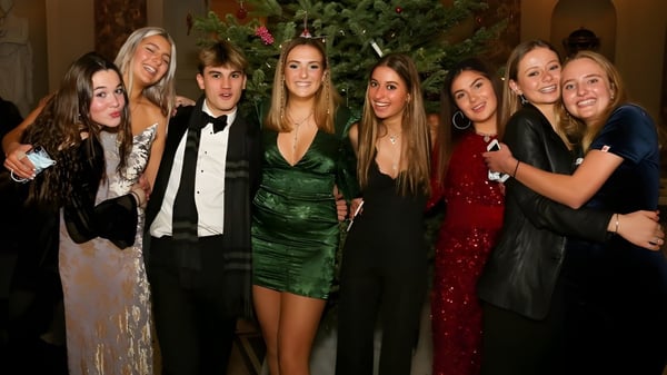 Schüler der Stephen Perse Foundation posieren bei der Weihnachtsfeier vor einem geschmückten Baum.