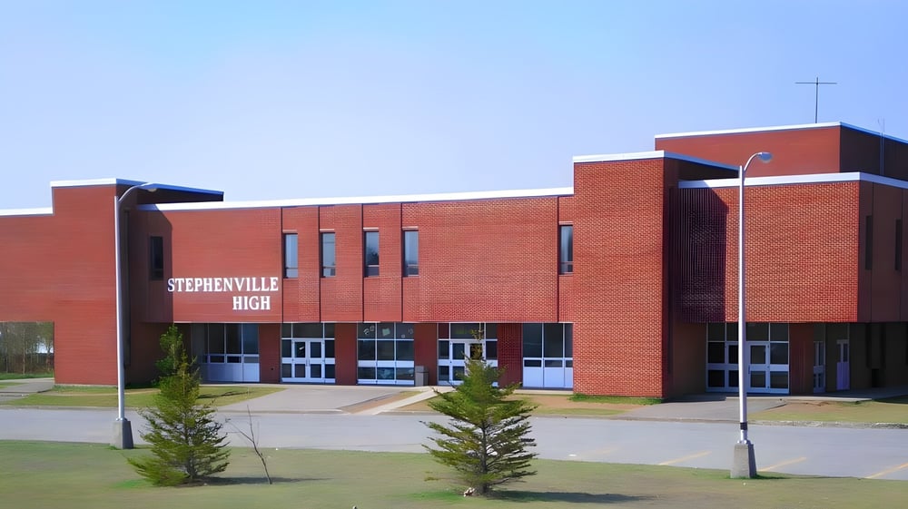 Das rote Backsteingebäude der Stephenville High School ist von Bäumen umgeben und steht an einer gepflasterten Fläche.