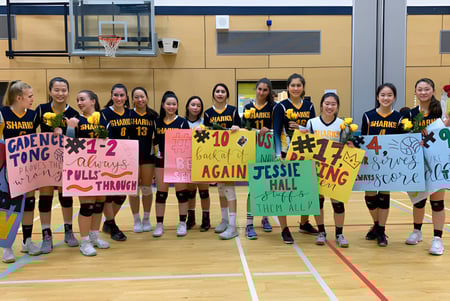 Eine Gruppe weiblicher Basketballspielerinnen der Steveston-London Secondary School steht mit Bannern in der Sporthalle.