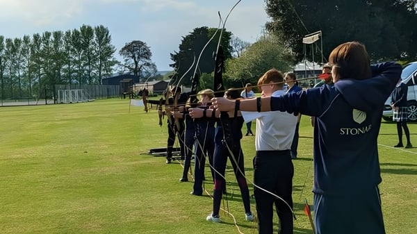 Schüler der Stonar School stehen auf einem Feld und schießen mit Bögen auf Zielscheiben.