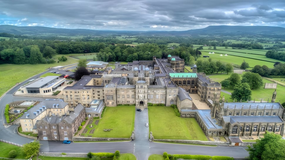 Das mittelalterliche Schloss auf dem Gelände des Stonyhurst College ist von grüner Landschaft und Hügeln umgeben.