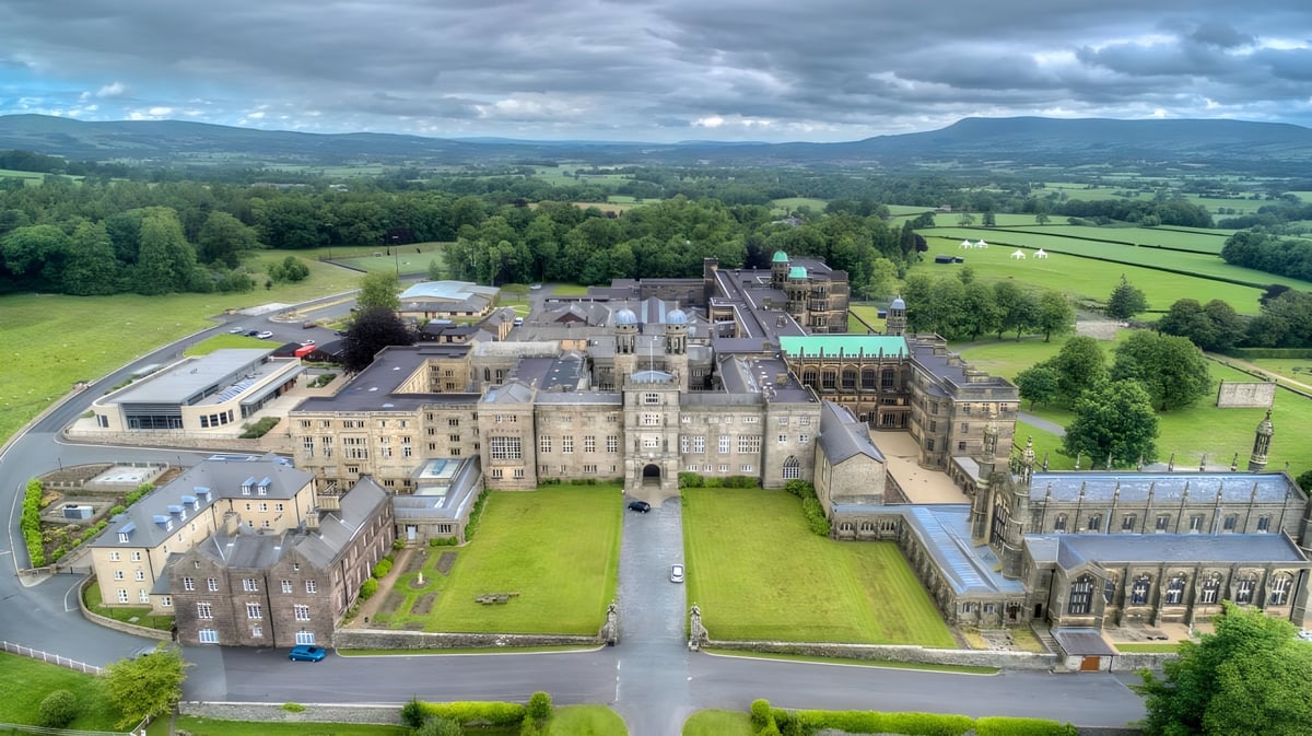 Das mittelalterliche Schloss auf dem Gelände des Stonyhurst College ist von grüner Landschaft und Hügeln umgeben.