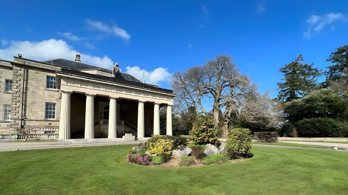 Das klassische Gebäude mit Säulen auf dem Campus der Stover School ist von einem gepflegten Rasen und großen Bäumen umgeben.