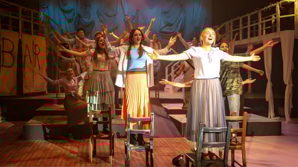 Eine Gruppe von Schülern der Stowe School führt auf der Bühne ein farbenfrohes Musical auf.