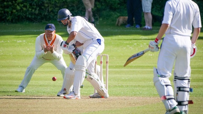 Schüler des Stratford College spielen ein Cricket-Match auf einem grünen Spielfeld.