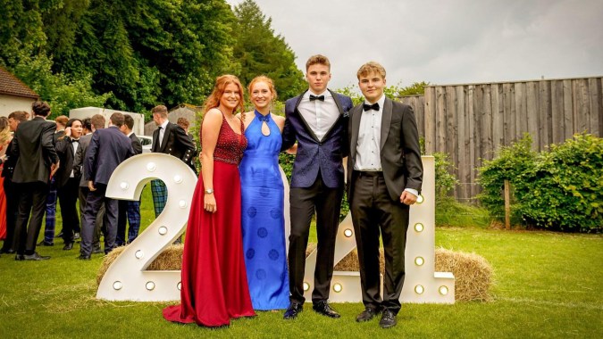 Eine Gruppe von Schülerinnen und Schülern des Stratford College steht in formeller Kleidung vor Bäumen und einem Zaun.