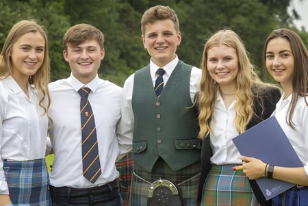 Fünf Schülerinnen und Schüler des Stratford College stehen zusammen in einem grasbewachsenen Waldgebiet.