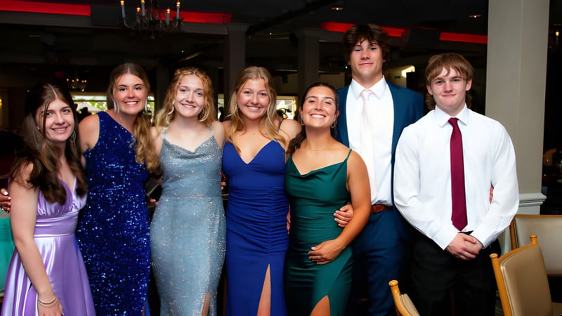 Schüler der Stratford District Secondary School posieren gemeinsam bei einer formellen Veranstaltung vor rotem Hintergrund.