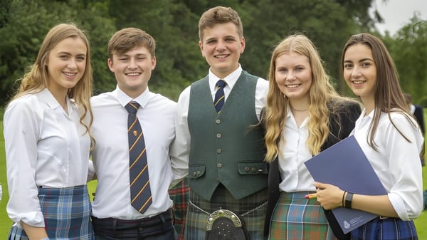 Eine Gruppe von fünf Schülerinnen und Schülern der Strathallan School steht gemeinsam draußen auf einer Grasfläche mit Bäumen.