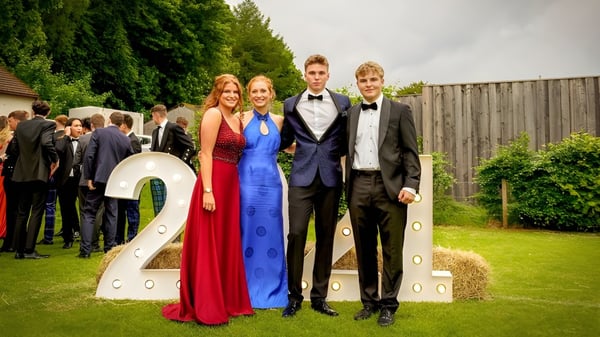 Eine Gruppe Schüler in festlicher Kleidung steht vor der großen Zahl 2 auf dem Gelände der Strathallan School.