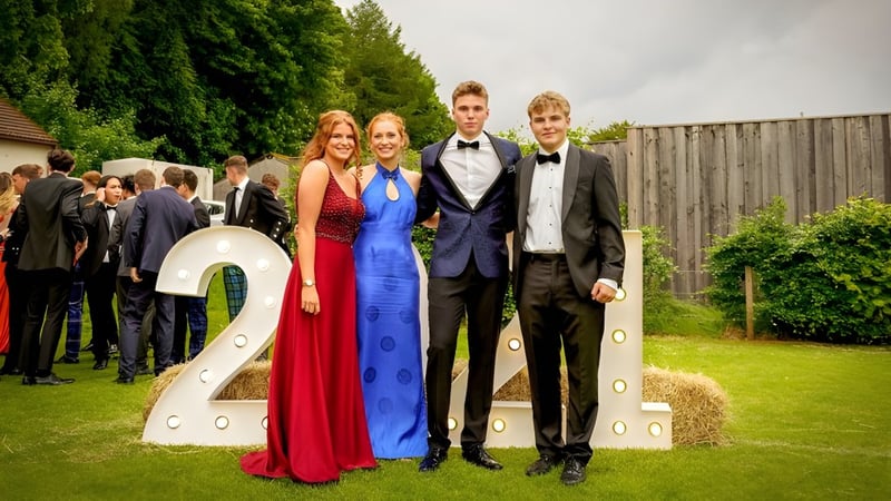 Eine Gruppe Schüler in festlicher Kleidung steht vor der großen Zahl 2 auf dem Gelände der Strathallan School.