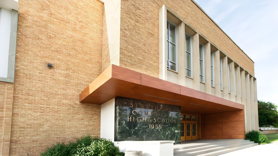 Das Backsteingebäude mit prominentem Eingang der Strathcona High School ist von Grünflächen umgeben.