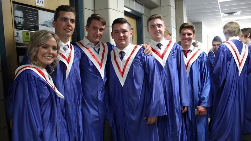 Schüler der Strathmore High School in blauen Abschlussmänteln stehen im Flur vor einer Tafel.