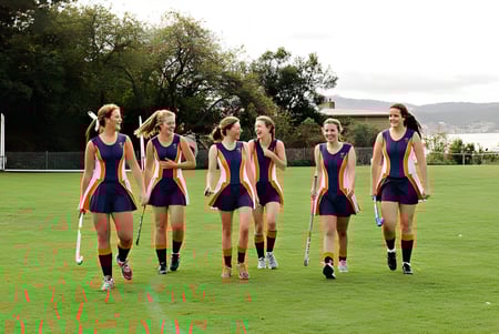 Eine Gruppe von Schülerinnen in Sportuniformen steht auf einem grünen Spielfeld am Stretton State College.