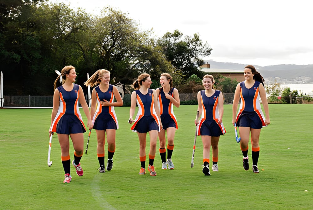 Eine Gruppe von Schülerinnen in Sportuniformen steht auf einem grünen Spielfeld am Stretton State College.