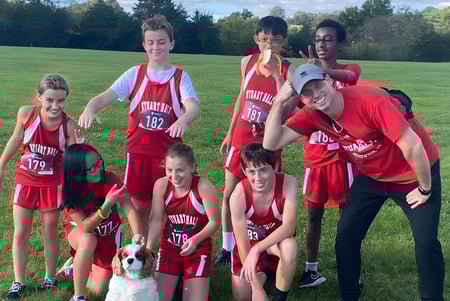 Eine Gruppe von jungen Athleten in roten Trikots posiert auf dem Spielfeld im Freien auf dem Gelände der Stuart Hall School.