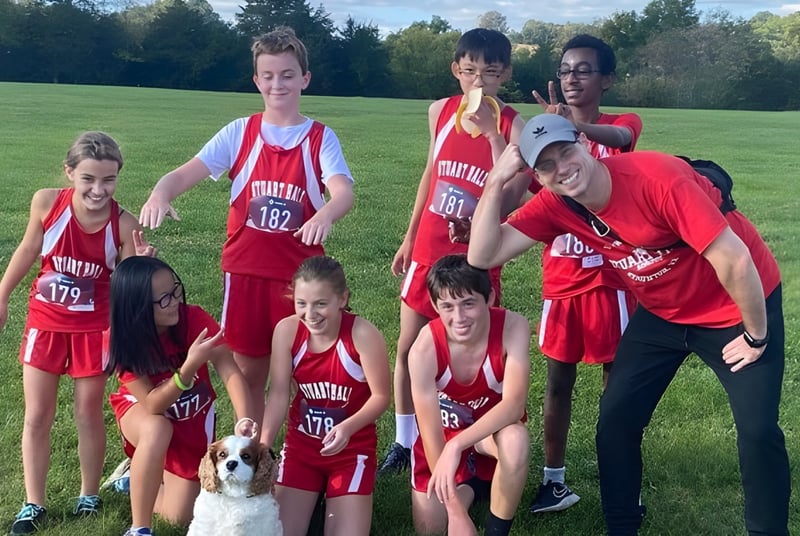 Eine Gruppe von jungen Athleten in roten Trikots posiert auf dem Spielfeld im Freien auf dem Gelände der Stuart Hall School.