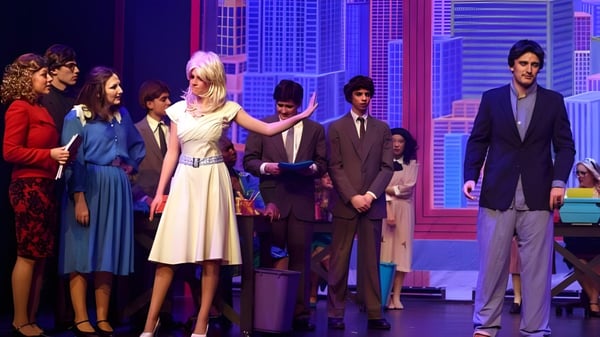 Eine Gruppe von Schülerinnen und Schülern steht auf der Bühne der Suffield Academy vor einer Stadtlandschaft als Hintergrund.