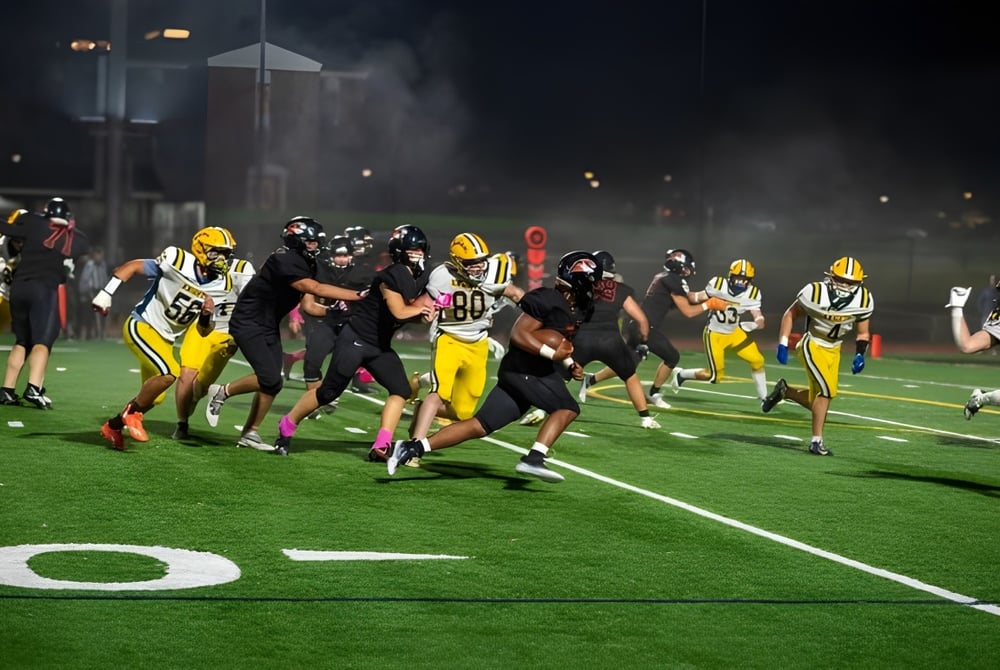 Schüler der Suffield Academy spielen ein Footballspiel auf dem beleuchteten Spielfeld bei Dämmerung.