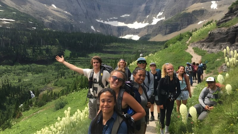 Eine Gruppe von Schülerinnen und Schülern der Sugarloaf Senior High wandert auf einem Pfad in einer bergigen Landschaft.
