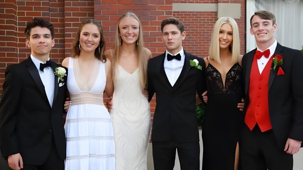 Eine Gruppe von Personen in formeller Kleidung posiert vor einer Backsteinwand auf dem Campus der Sugarloaf Senior High.