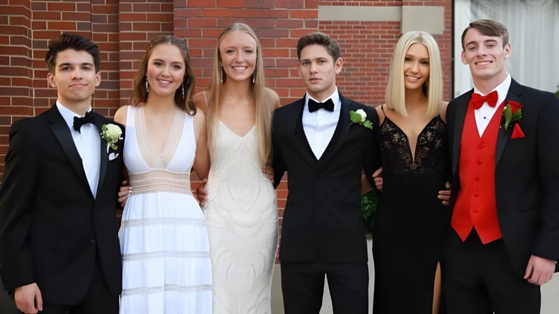 Eine Gruppe von Personen in formeller Kleidung posiert vor einer Backsteinwand auf dem Campus der Sugarloaf Senior High.
