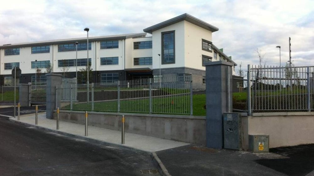 Das moderne mehrstöckige Gebäude von Summerhill College mit einem abgeschlossenen Eingang und einem umzäunten Rasenbereich im Vordergrund.