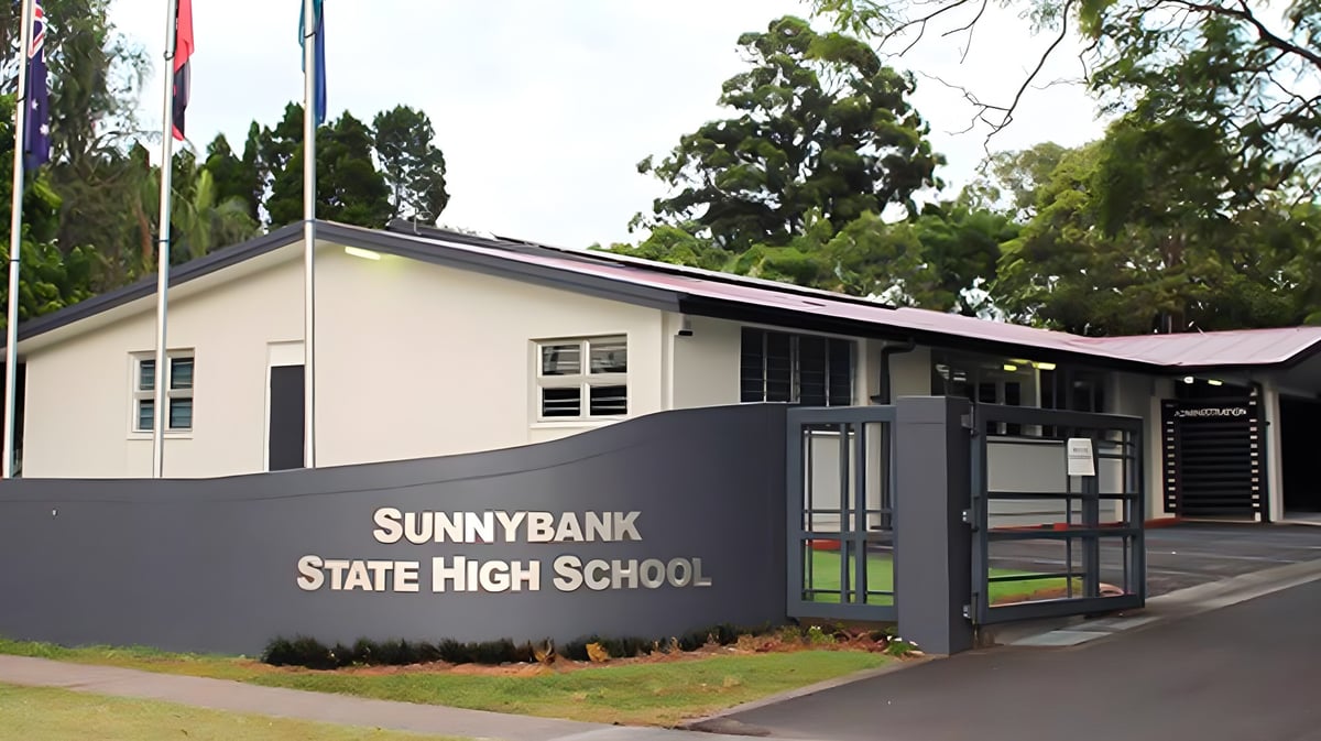 Das moderne Schulgebäude der Sunnybank State High School ist von grünen Bäumen umgeben.