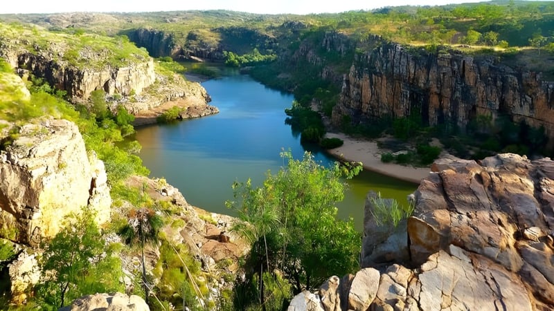 Eine felsige Landschaft mit steilen Klippen und einem türkisfarbenen Fluss führt durch ein grünes Tal auf dem Gelände der Sunshine Beach State High School.