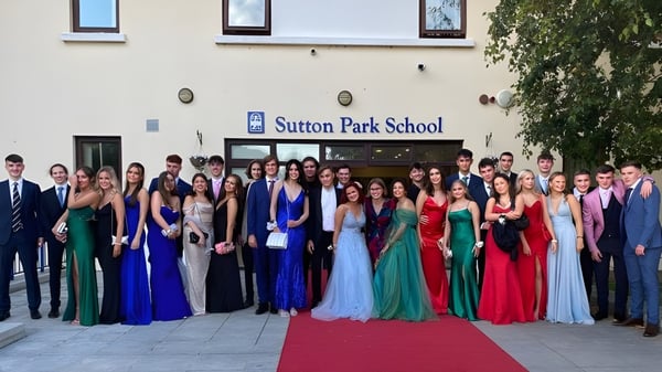 Schüler der Sutton Park School in Dublin stehen in feiner Abendgarderobe vor dem Schulgebäude auf einem roten Teppich.
