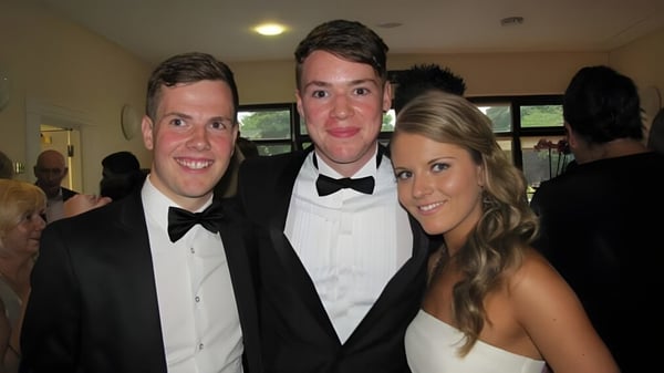 Drei formell gekleidete Personen posieren gemeinsam bei einer Feier auf dem Campus der Sutton Park School.